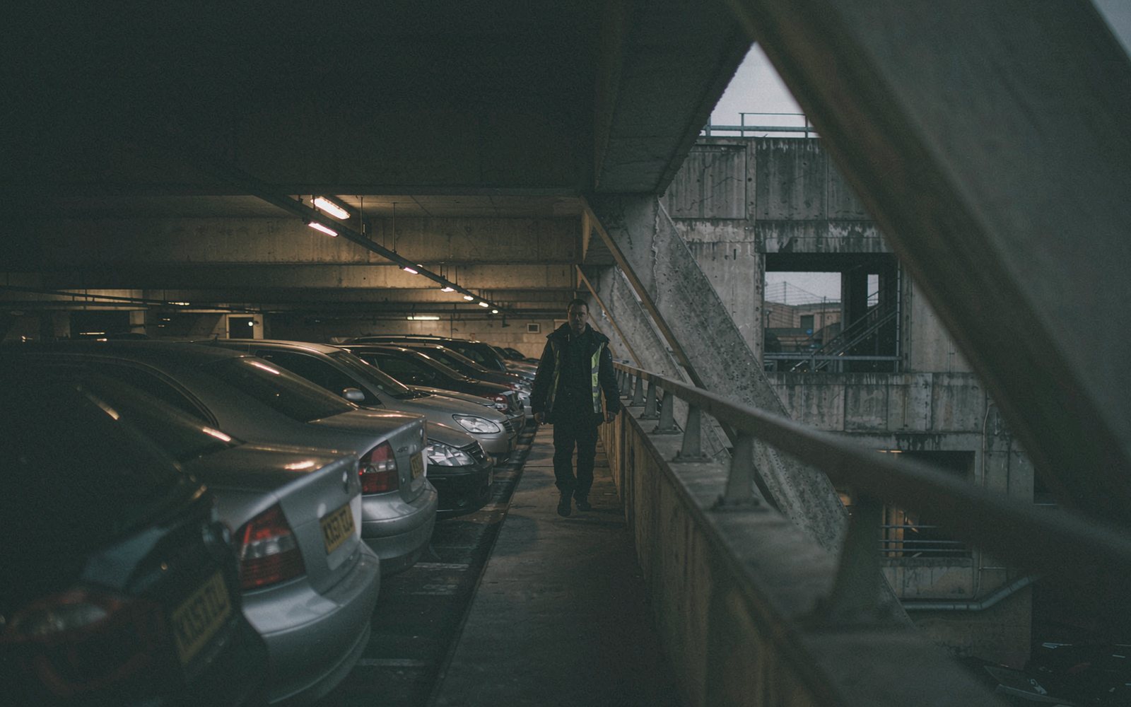 Multi-storey car park patrol between parked cars at dusk